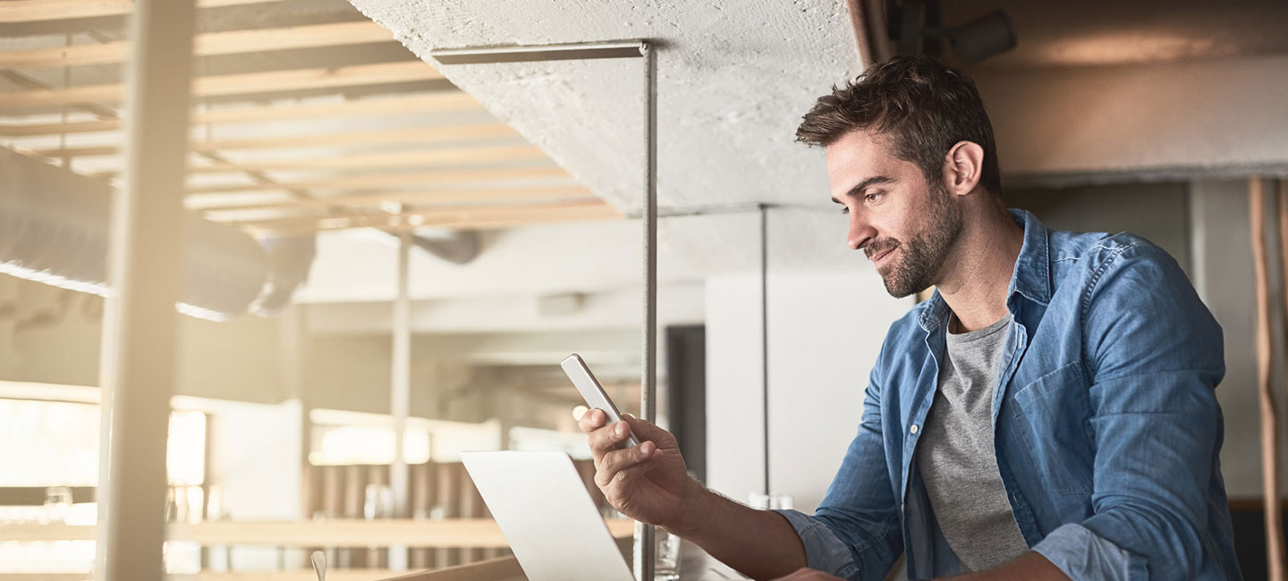 Man using smartphone and laptop in an office renovation